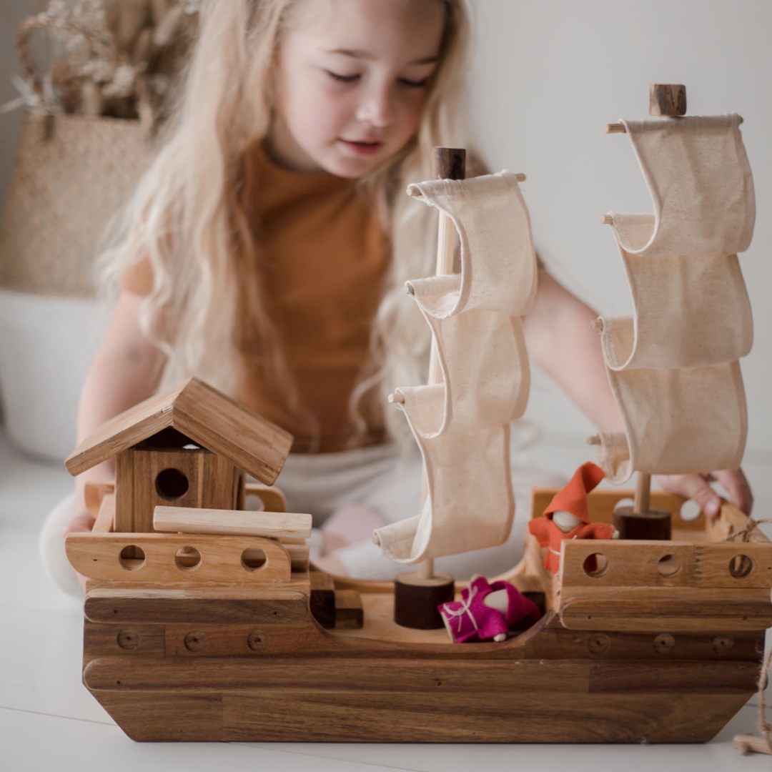 Girl playing with Wooden pirate ship with two sets of sails from QToys