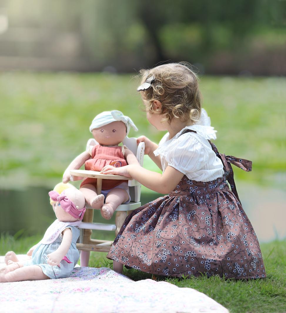 Baby Aria and friend sitting in a high chair while young girl pretends to feed her during pretend role play