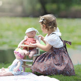 Baby Aria and friend sitting in a high chair while young girl pretends to feed her during pretend role play