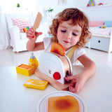 Child pushing down lever of Hape Pop-Up Toaster popping the toast out
