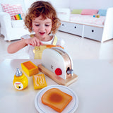 Child using knife to butter piece of pretend toast from Hape Pop-Up Toaster Set