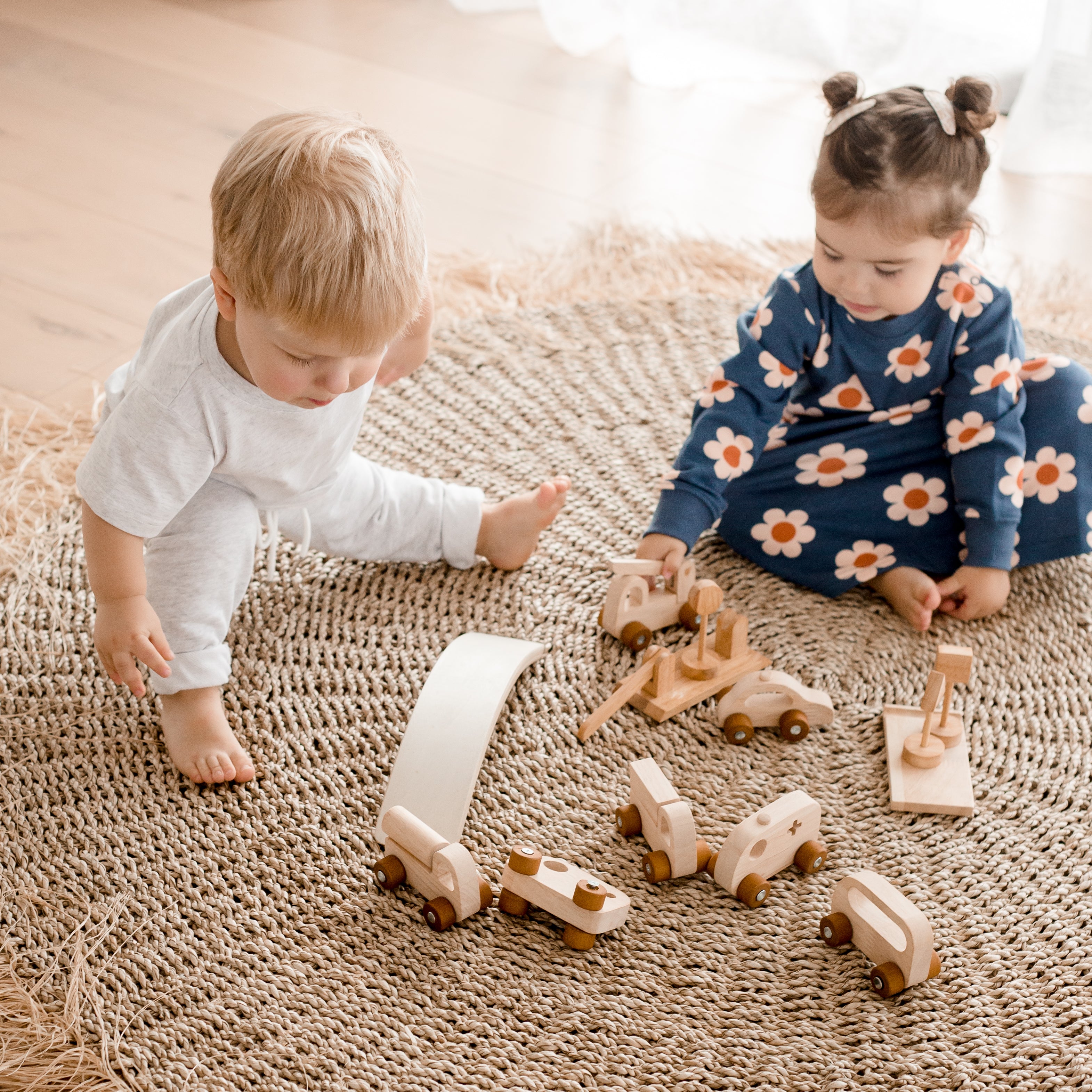 Girl and boy playing with cars and trucks from wooden vehicle play set from QToys