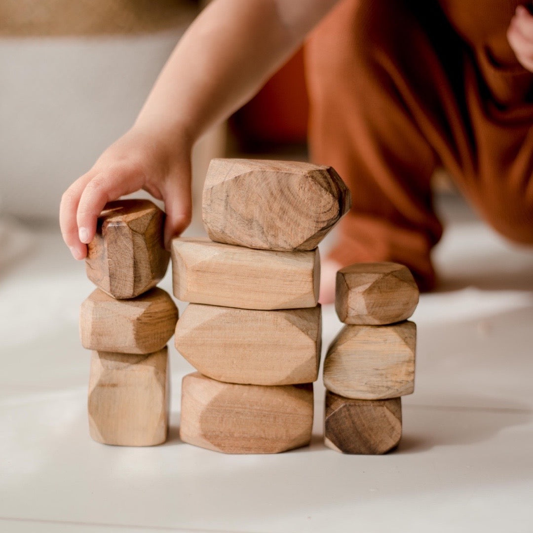 10 natural wooden gems from QToys being stacked in towers by a toddler