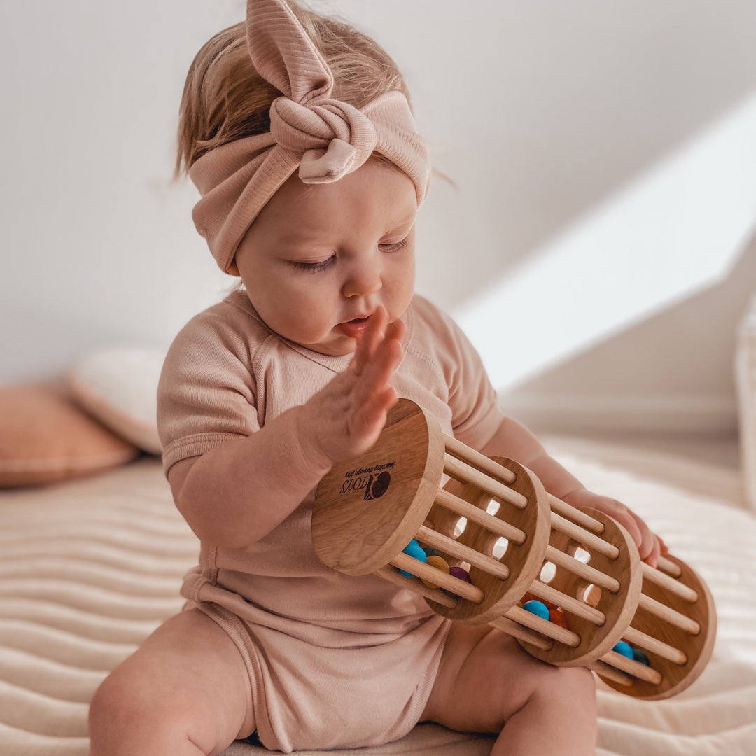 Baby playing with wooden rain maker with colourful wooden balls from QToys