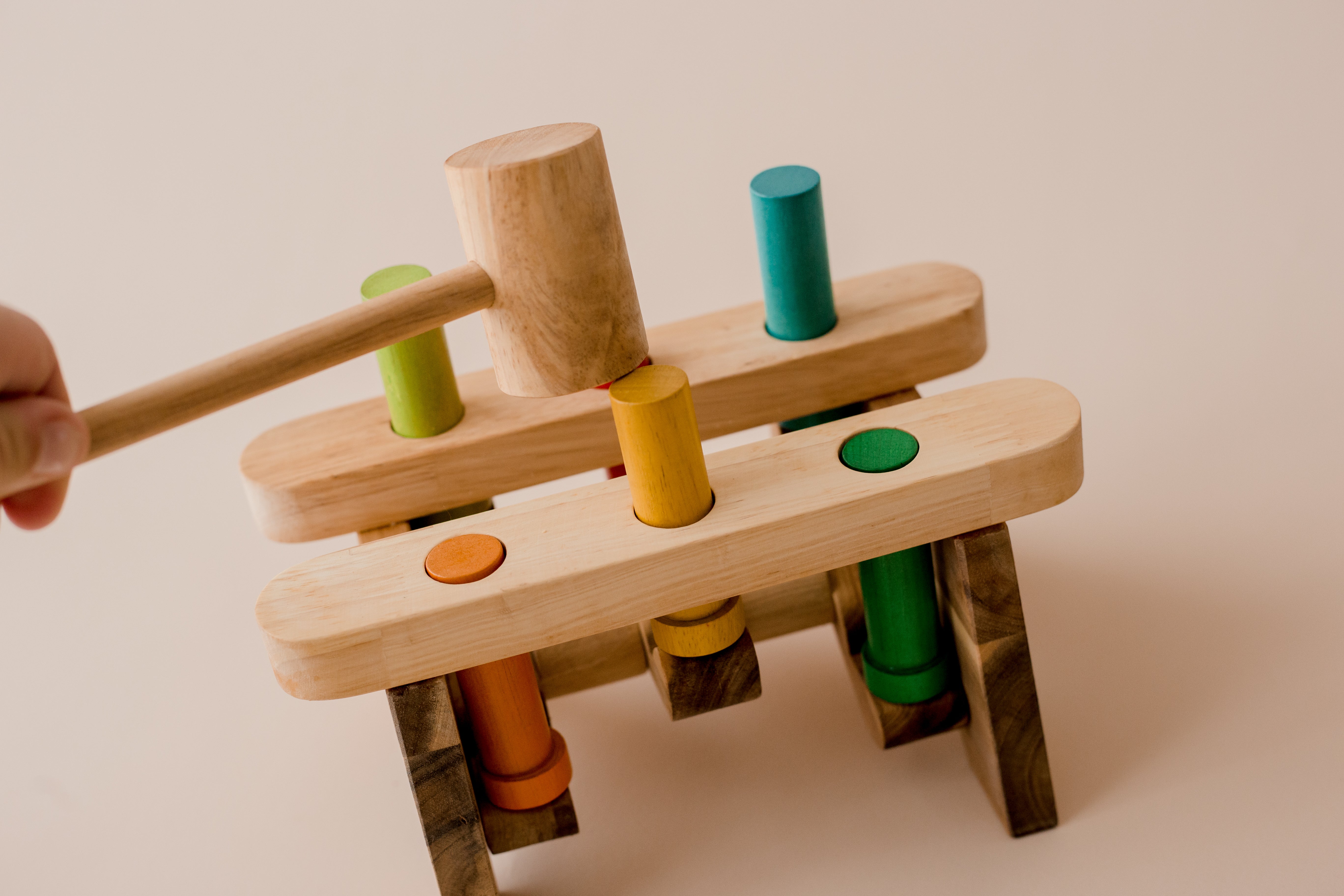 Shows a hand using the hammer to pound the pegs of the wooden pound a peg toy from QToys. Perfect for toddlers