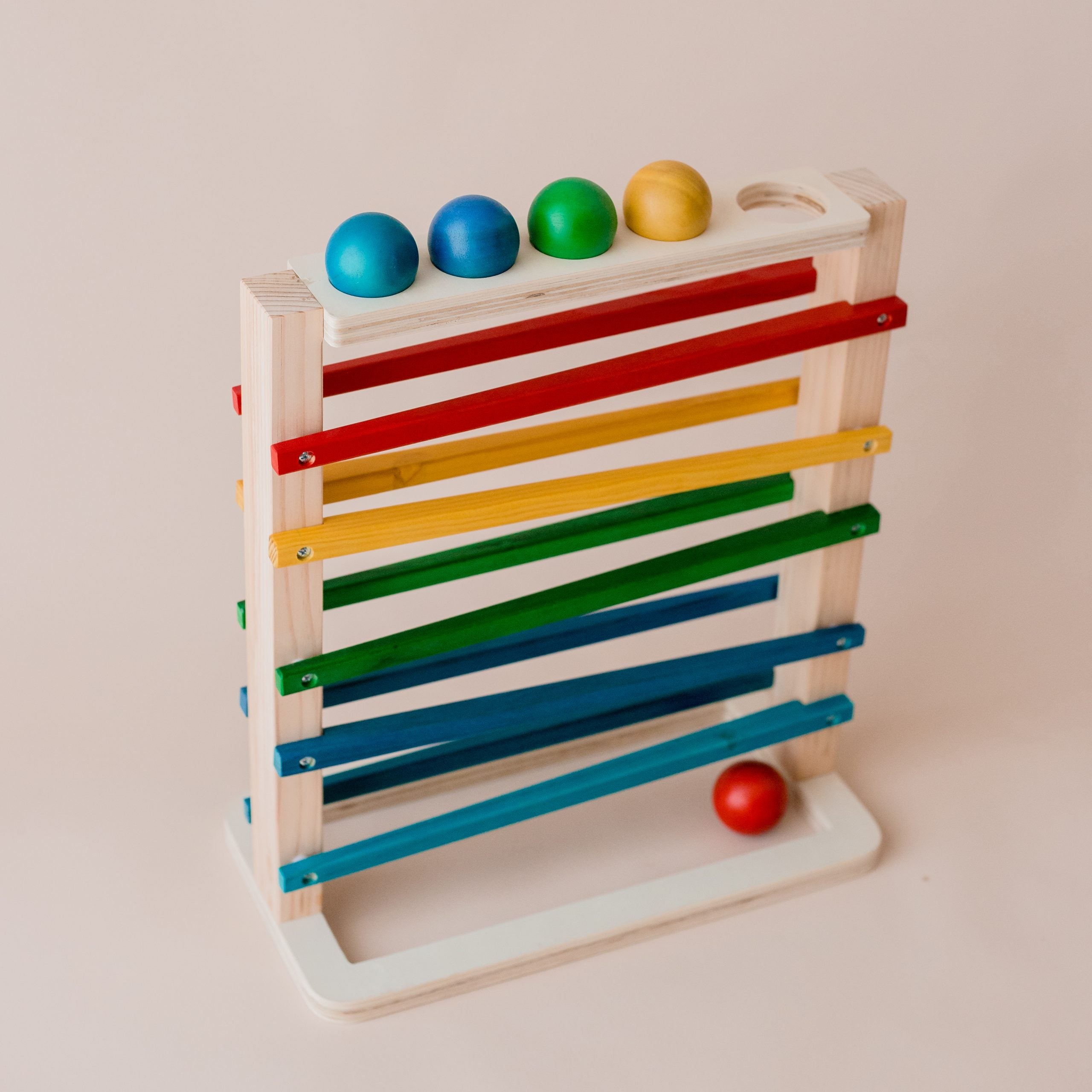 Colourful wooden track a ball rack toy from QToys. Shown with 5 balls. 2 blue, green, yellow and red.