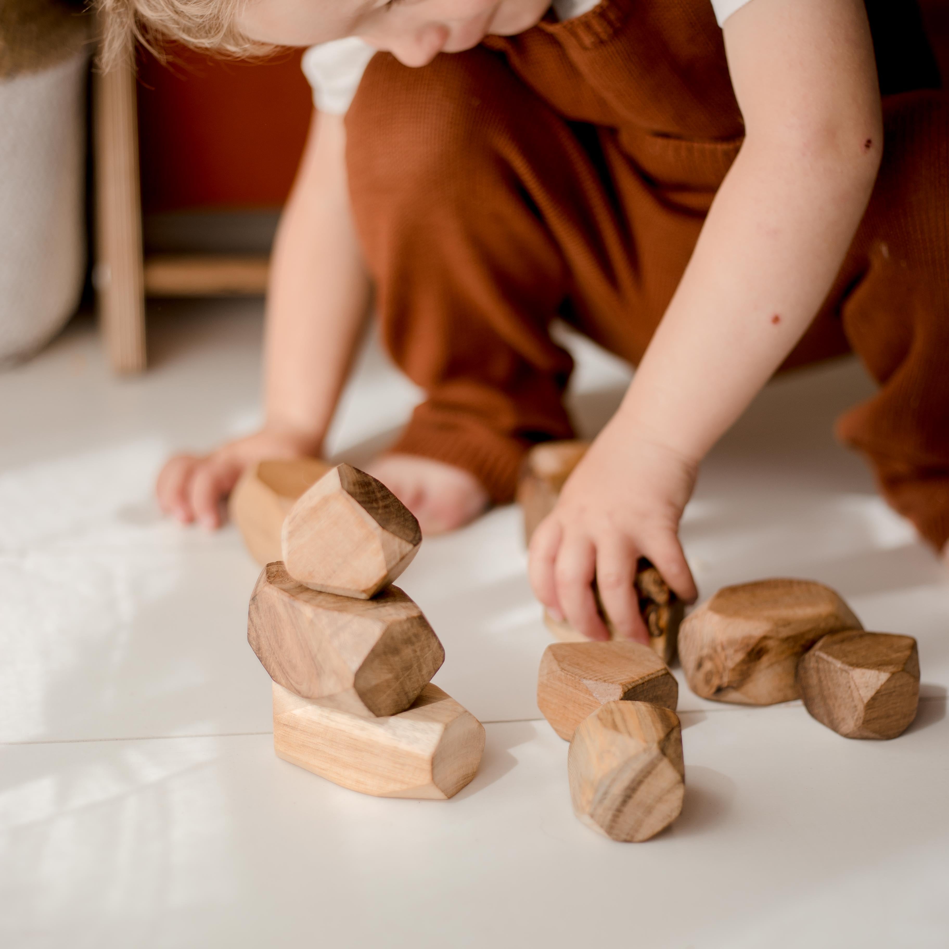 A preschooler building a tower from the natural wooden gems from QToys