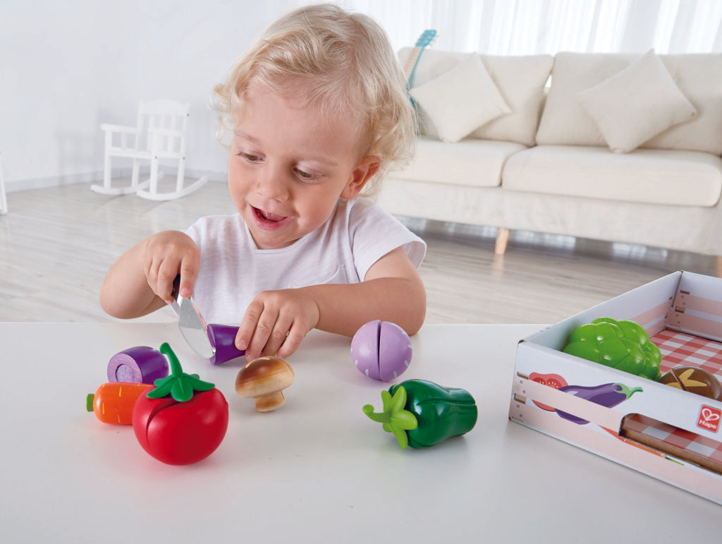 Boy engaging in role play cutting egg plant with pretend knife