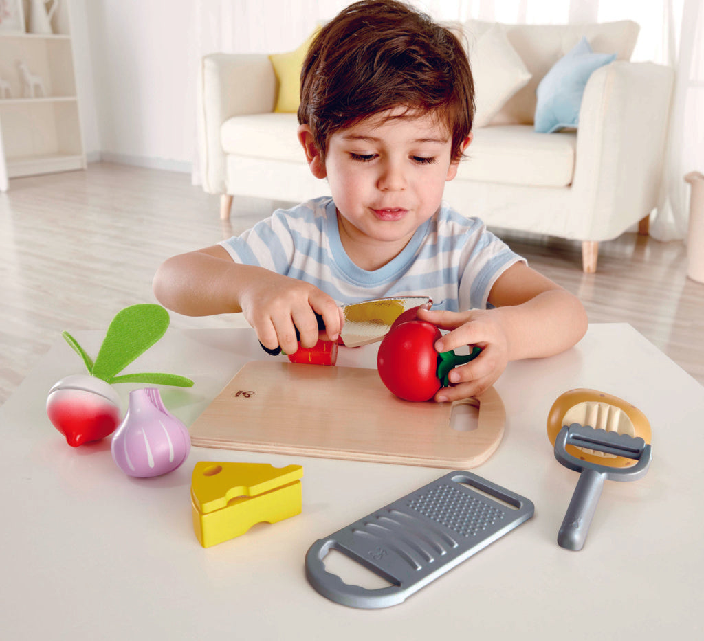 Boy chopping tomato of Hape cooking essentials play set. 