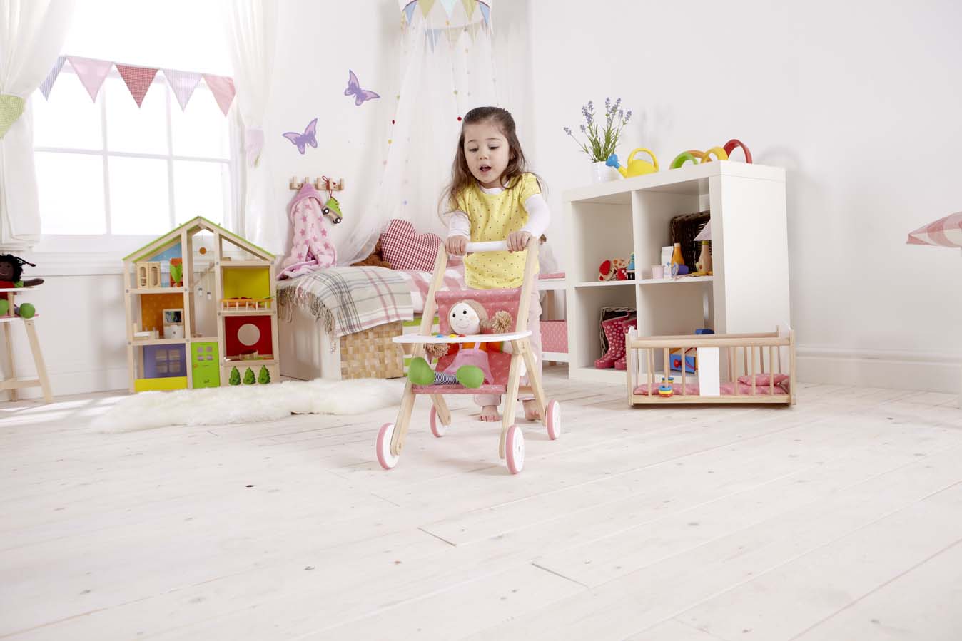 Girl pushing doll around in Hape stroller