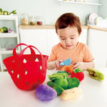 Child cutting carrot in half of Hape toddler vegetable basket