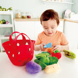 Child cutting carrot in half of Hape toddler vegetable basket