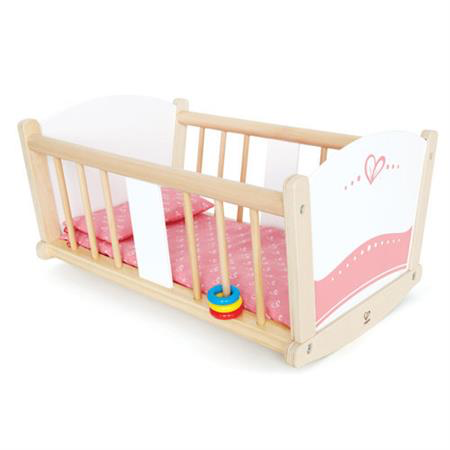 Hape rock a bye cradle with pink mattress and cushion and ring rattle attached to rails. 