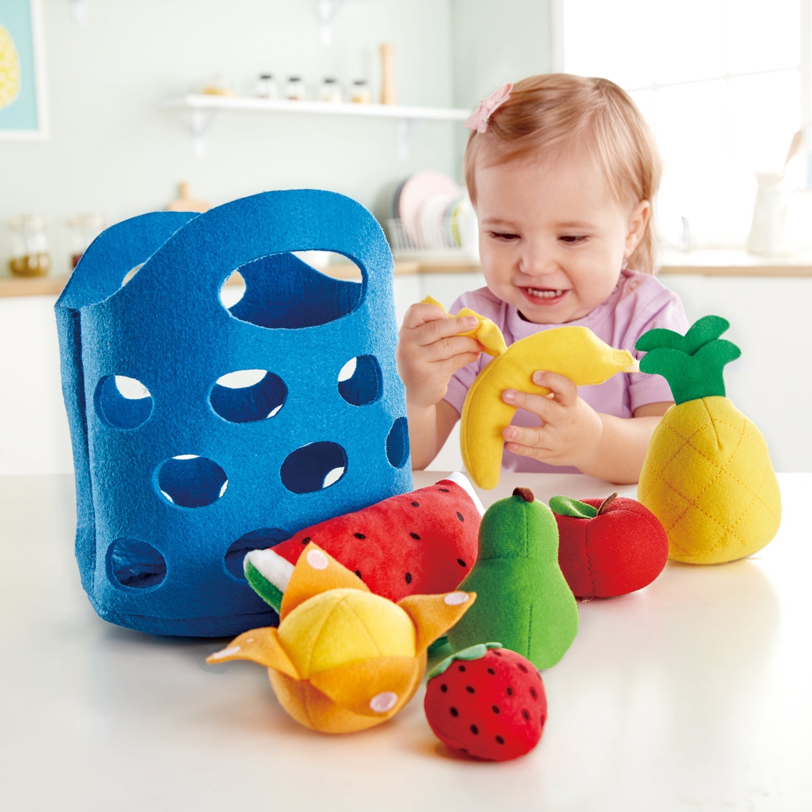 Girl shown peeling banana from Hape toddler fruit basket