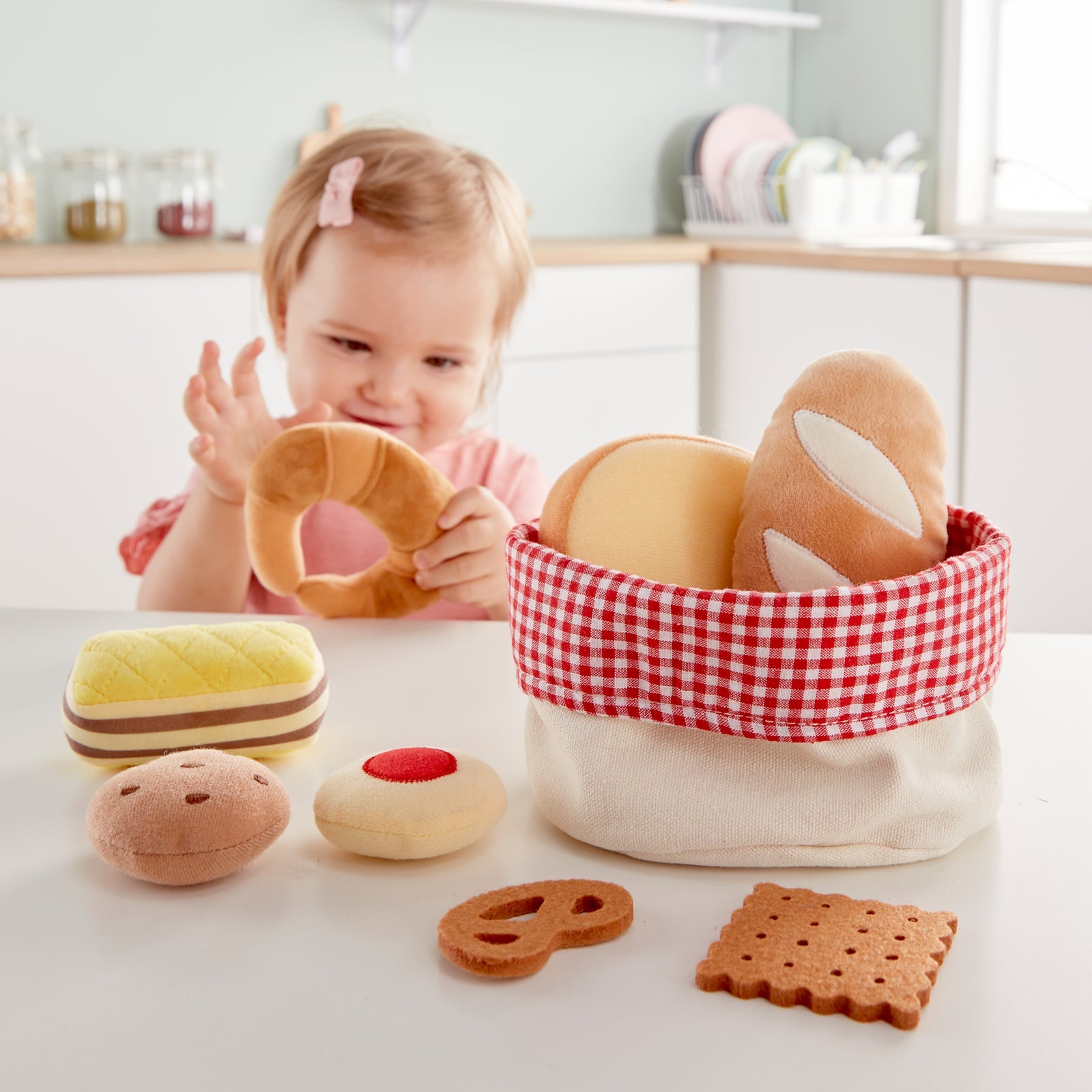 Girl examining croissant of Hape toddler bread basket